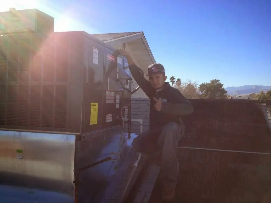 HVAC technician performing Air Duct Cleaning on a rooftop unit in New London